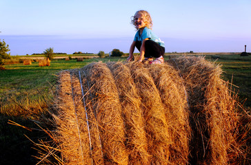 The curly baby sits on hay