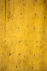 textured background. The wall is wooden with holes from nails, in old yellow paint.