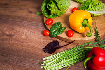 Yellow pepper and other vegetables on brown wooden background