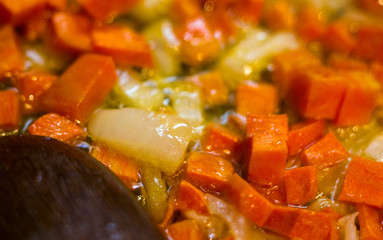 Frying finely chopped carrots and onions in boiling oil, close-up