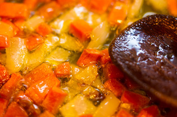 Frying finely chopped carrots and onions in boiling oil, close-up