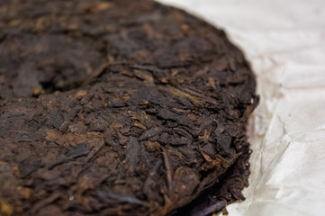 Chinese pressed puer tea on wrapping paper, close-up, macro