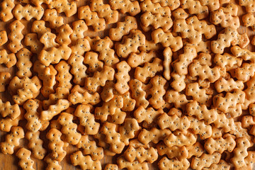 Composition of crackers with poppy seeds, spread out on a wooden background