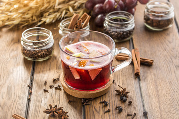 Cup of hot mulled red wine and wheat spikes on wooden table