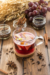 Cup of hot mulled red wine and wheat spikes on wooden table