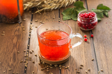 Cup of tea with red berries and wheat spikes on wooden table
