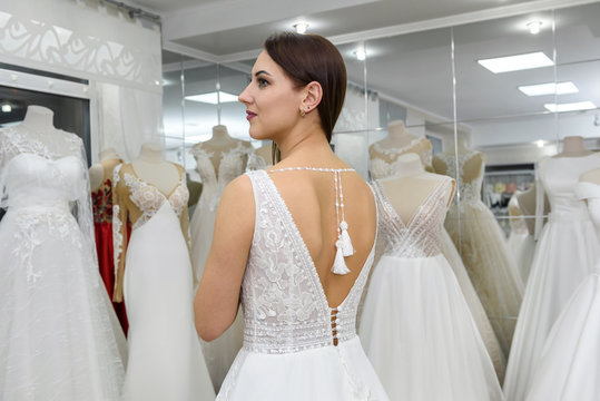 Girl trying on wedding dress in salon, standing back