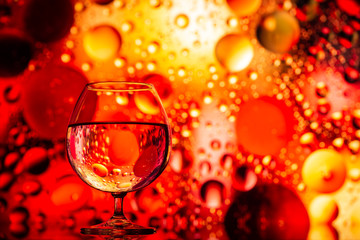 transparent glass with water and oily drops on bright  background 