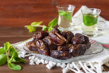 Iftar or Suhoor snack close up of dates on glass plate with mentha tea on background , Ramadan concept