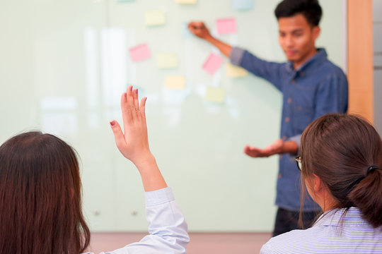 close up young asian woman hand raised for asking instructor or manager about working project in meeting room , thinking outside the box concept