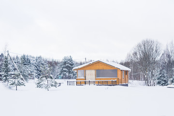 A typical suburban two-storey wooden house, the cottage near the forest in winter