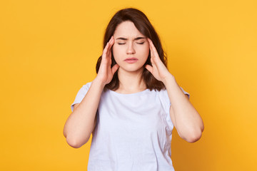 Image of young good looking brunette female stands with closed eyes isolated over yellow...