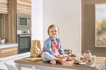 Fototapeta na wymiar Happy cute and beautiful child smiling at home playing in the kitchen