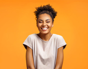 Overjoyed girl with curly hairstyle laughs happily. Photo of african american girl wears casual...
