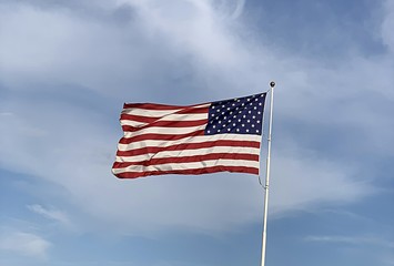 American flag against blue sky and clouds background 