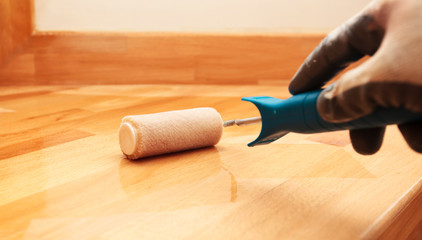 The painter  paints a varnish wooden board by roller