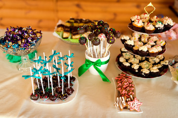 Elegant and stylish candy bar with cakes, muffins, candies, cookies sweets, lollipops. Wedding banquet decoration.