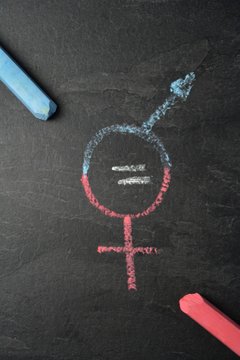 On a dark marble surface, the symbol for man and woman was recorded with different chalks and an actual match between them - concept for the equality of men and women