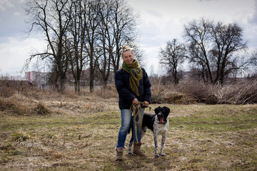 Fototapeta premium Young brunette girl with her dog walking in autumn park.
