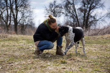 Young brunette girl with her dog walking in autumn park.