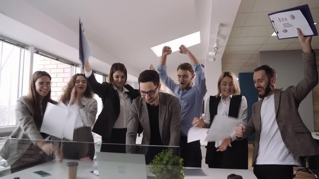 Business team throw papers into air, and enjoy the end of a successful project