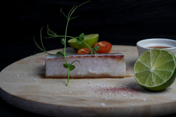 Fresh pike perch on a wooden Board with lime, thyme, cherry tomatoes and red sauce
