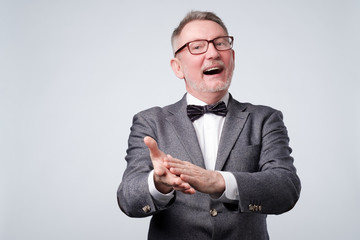 Handsome senior man in glasses and suit applauding