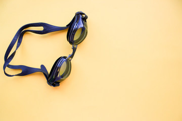 Black swimming goggles on yellow background