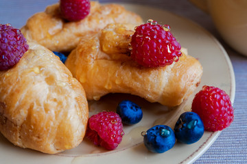 delicious summer juicy blueberry and raspberry berry with honey droplets on a fresh croissant