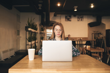 A woman on her phone, behind her laptop