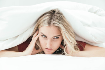 Fototapeta premium Grumpy blonde girl under white covers