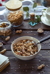 Bowl with home made granola and spoon on brown wooden table background, healthy breakfast concept, cereal granola food with nuts seed organic muesli morning diet oat meal for health vertical view