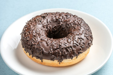 Chocolate donut on a white plate.