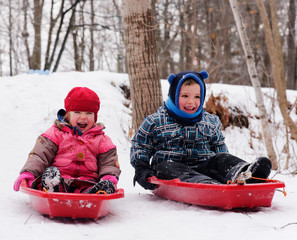 Brother and sisters (5 and 3 yrs old) sledging together in Quebec in winter