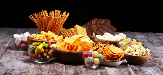 Salty snacks. Pretzels, chips, crackers in wooden bowls on table