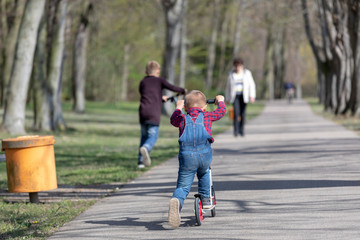 little boy play balance scooter at spring in park