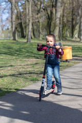 Obraz premium little boy play balance scooter at spring in park