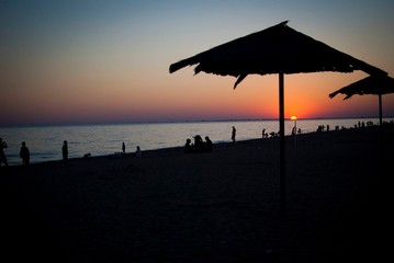 Silhouette on the beach with sunset on the sea with umbrella.