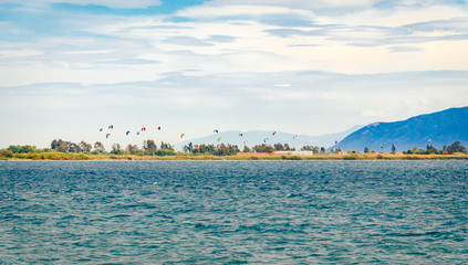 People kitesurfing under a dramatic cloudy sky at Cape Drepano Greece