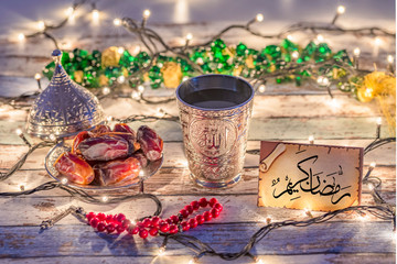 Greeting card with arabic text "Ramadan Kareem" with dates, rosary, and water cup with Allah text in arabic