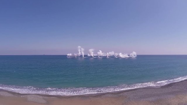AAV 7A1 vehicles arriving to the coast while naval mines explode