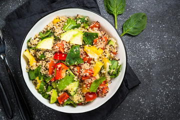 Quinoa salad with fresh vegetables on black.