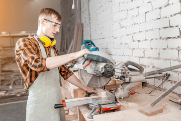 Fototapeta premium Male craftsman working with automated saw machine in factory or workshop