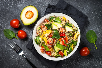 Quinoa salad with fresh vegetables on black.