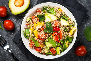 Quinoa salad with fresh vegetables on black.