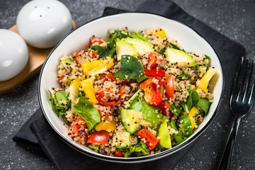 Quinoa salad with fresh vegetables on black.