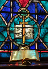 Colored light from stained glass window in methodist church falls across open bible