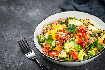 Quinoa salad with fresh vegetables on black.