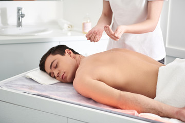 Obraz na płótnie Canvas Therapist making oil massage to young man