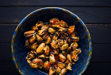 Canned mussels with oil in a bowl top view